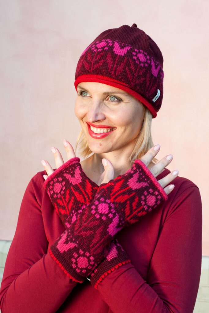 a woman wearing red lipstick smiling in a red wool hat with tulips