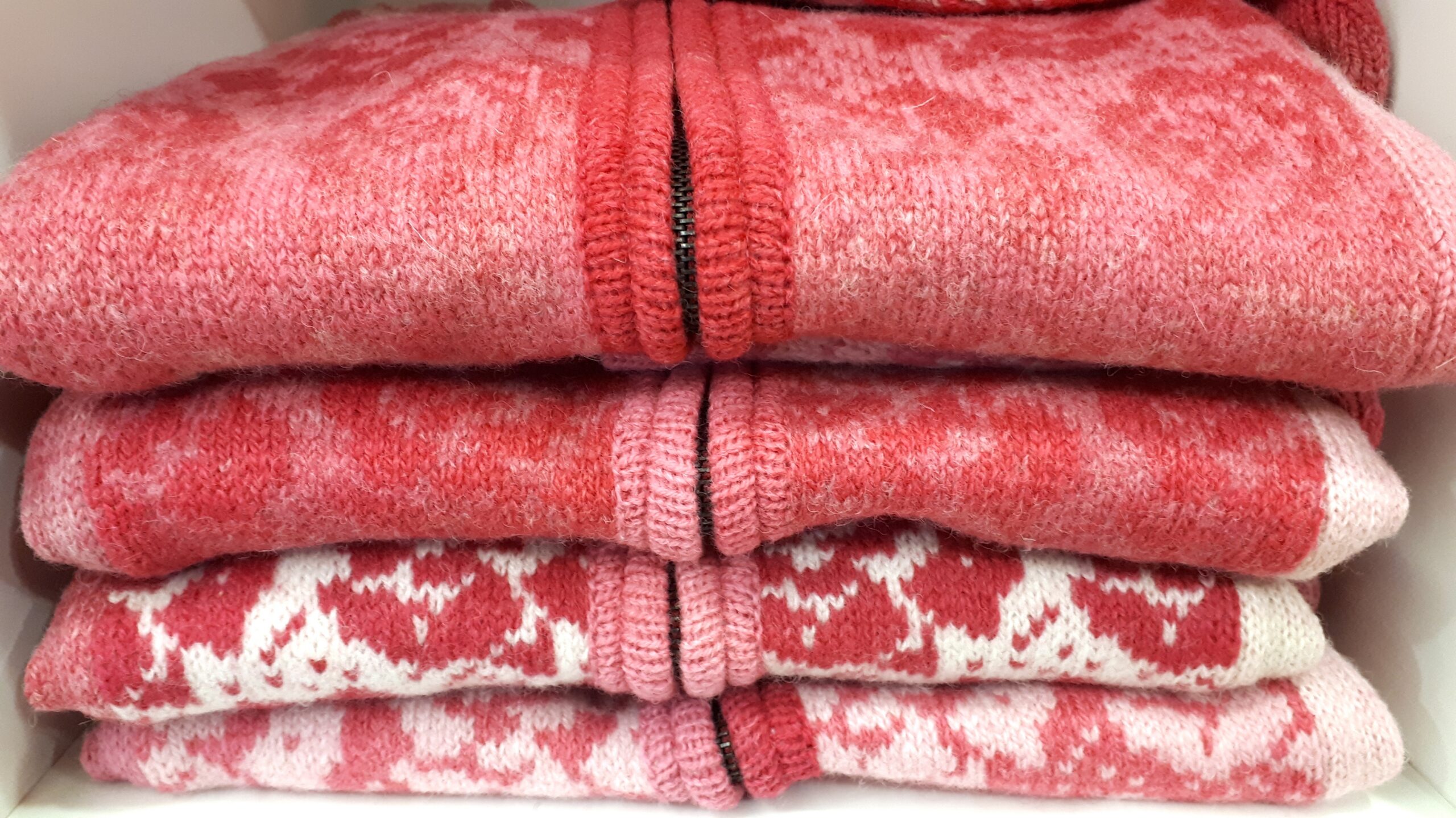 4 pink and white wool cardigans stacked on top of each other