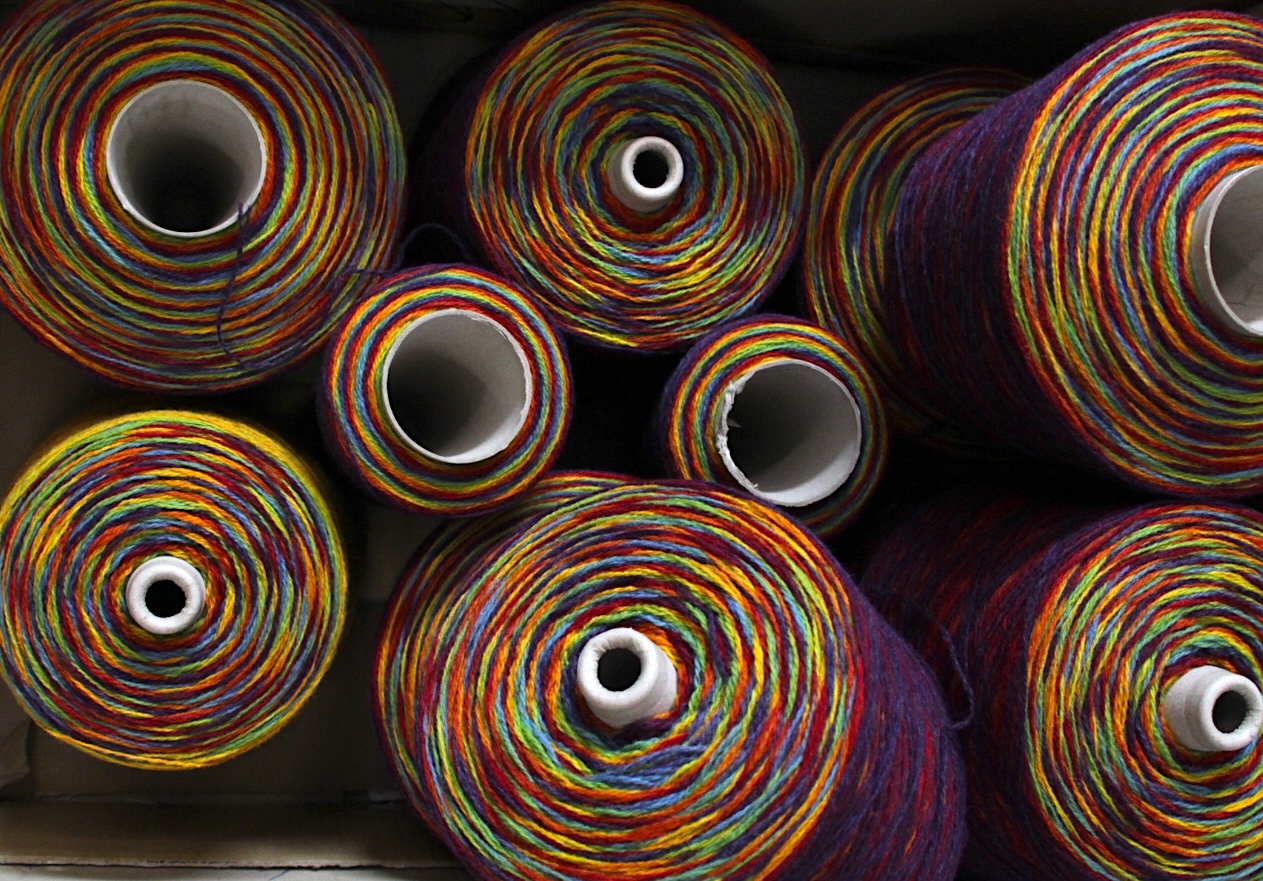 top view of rainbow coloured gradient wool yarn in cones