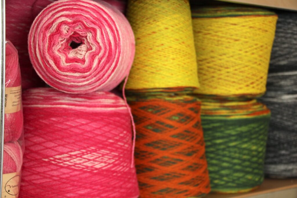 big cones of pink and green pure wool gradient yarn on a shelf