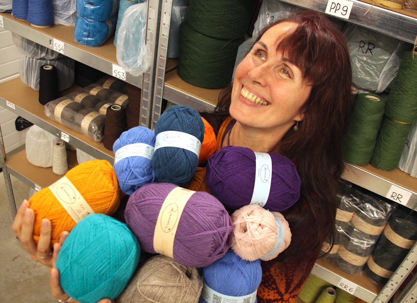 woman holding colourful skeins of pure sheep yarn and laughing