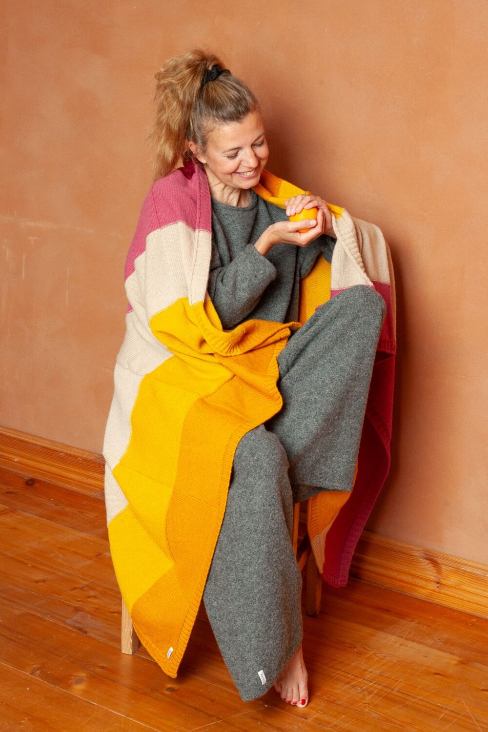 model sits with a wool throw blanket with stripes