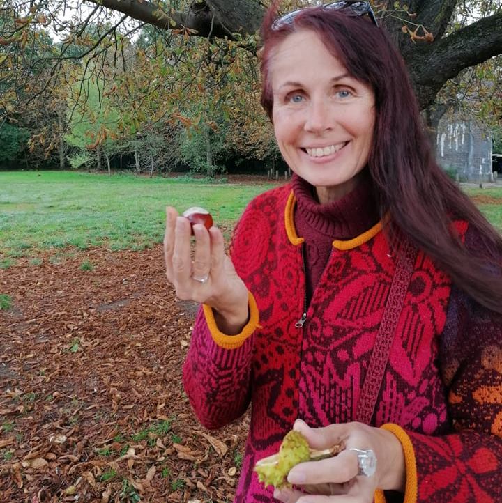 fashion designer kauni holding a chestnut under an autumn tree