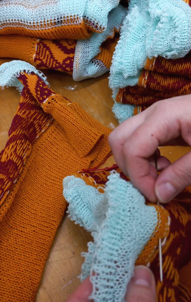 sewing lady sewing an orange coloured wool knit sweater or poncho