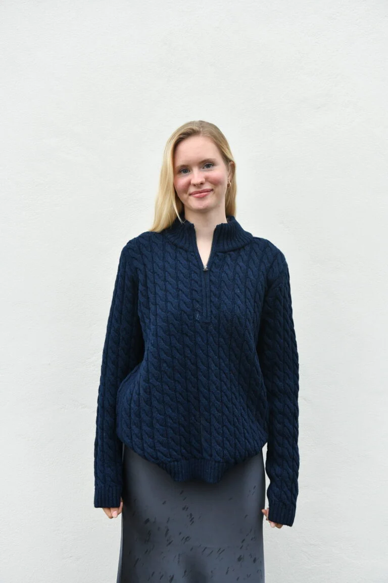 Woman wearing the dark blue cable-knit wool sweater oversized in size XL, front view with the zip collar slightly open